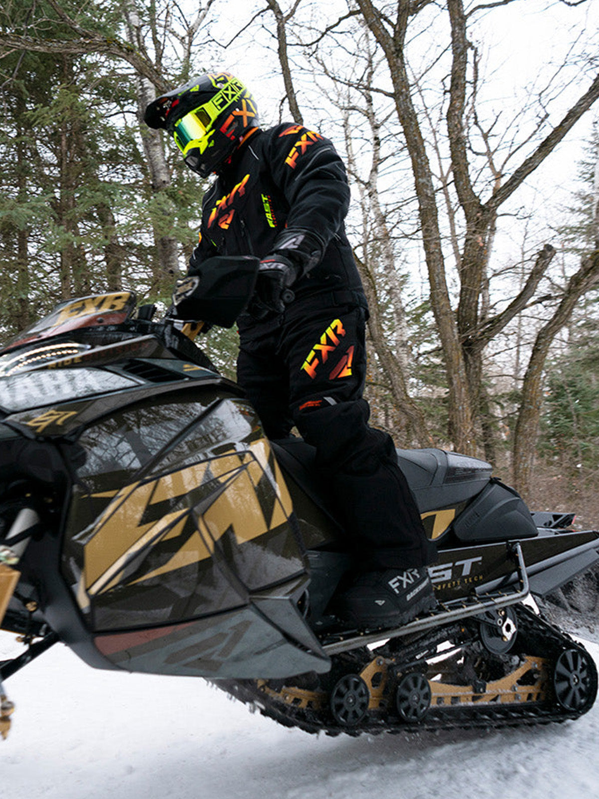 Action image of a guy snowmobiling on a trail wearing an FXR gear from FXR's Performance Trail collection